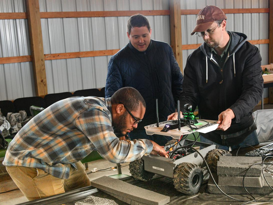 (From left) Army C5ISR Center employees Donovan Sweet, Rob Beckinger and Dan Lenhardt assess a robotic vehicle for the C4ISR Modular Autonomy project at Camp Grayling, Michigan. Under the Army vision, multiple robotic vehicles may be remotely controlled by the crew of a manned combat vehicle. Credit: Conrad Johnson, Army public affairs official​