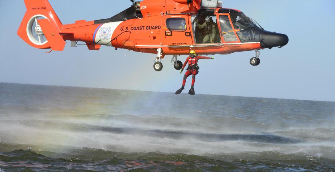 A U.S. Coast Guard rescue swimmer jumps out of an MH-65 Dolphin helicopter during a training exercise. Artificial intelligence-driven human forensics technology has helped the maritime service track down people accused of making hoax mayday calls, which cost tens of thousands of dollars and distract from the Coast Guard’s mission. Coast Guard photo
