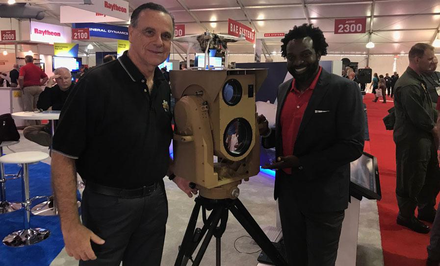 Two Boeing employees, Jerry Drelling (l), external communications, and Rhoan Boucher, weapons programs, Global Sales & Marketing Team, stand next to Boing’s compact laser weapon system, known as CLWS. CLWS offers a powerful, yet manportable solution to unmanned aerial vehicle threats, according to the company. Credit: Boeing