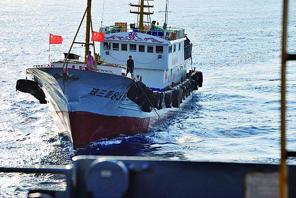A crewmember aboard a Chinese trawler tries to snag the towed acoustic array of a U.S. Navy ocean surveillance ship in international waters in the South China Sea.