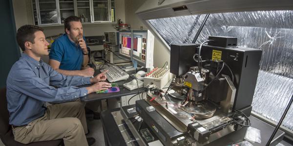 Sandia National Laboratories researchers Jon Ihlefeld (l) and David Scrymgeour use an atomic-force microscope to examine changes in a material’s phonon-scattering internal walls, before and after applying a voltage.
