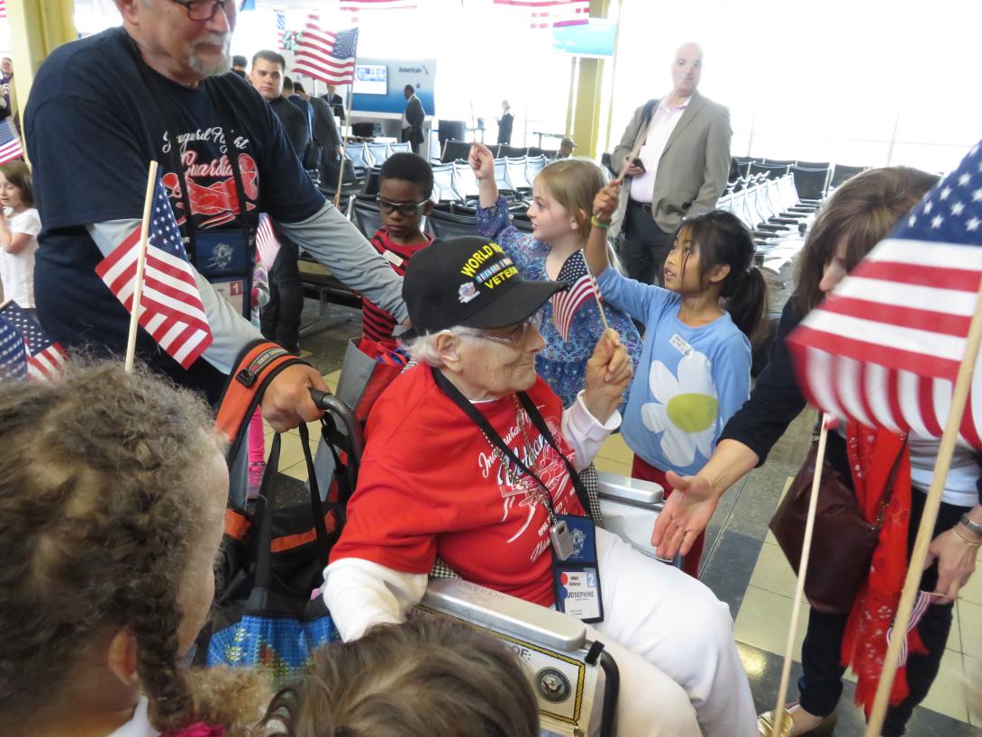 World War II veteran Josephine Renshaw and her Honor Flight Guardian make their way through the path created by hundreds of grateful greeters young and old. 