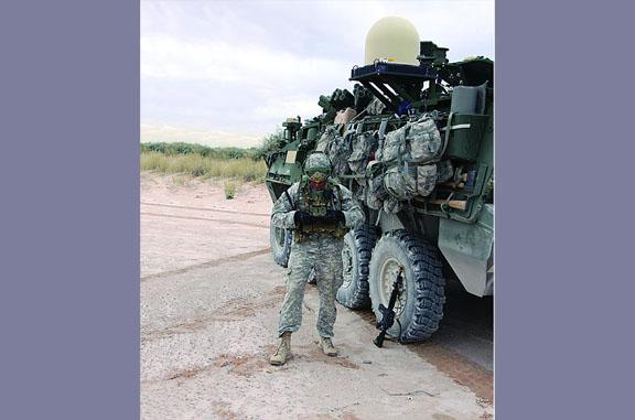 A 2nd Brigade, 1st Armored Division Soldier stands before a Stryker vehicle integrated with Warfighter Information Network-Tactical Increment 2 mobile network equipment and receives data from his handheld Nett Warrior device during last fall’s Network Integration Evaluation 14.1.