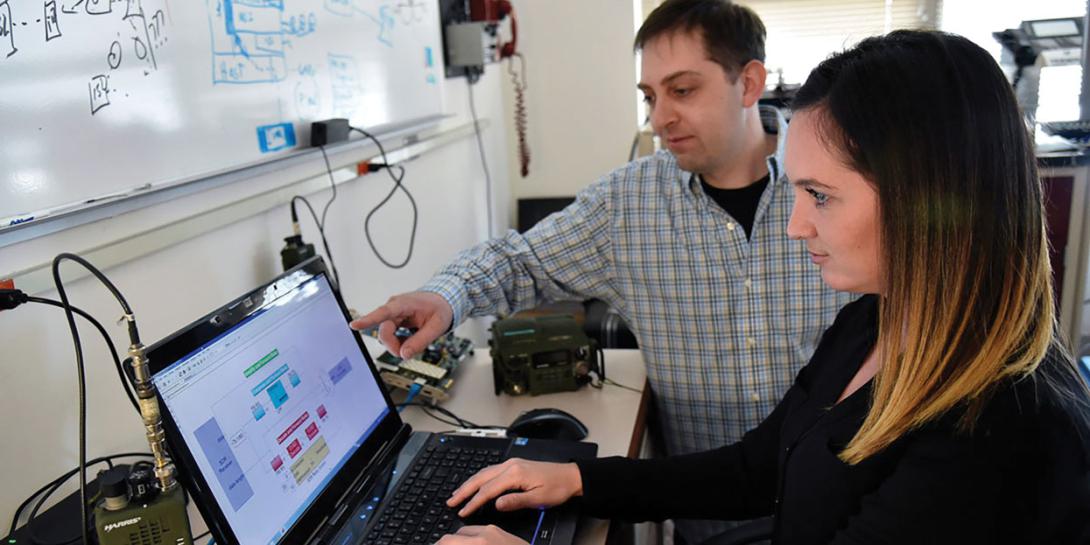Aaron Cohen, computer engineer and electrical engineer at the U.S. Naval Research Laboratory, discusses radio frequency relay testing with Amanda Bowling. To improve long-range communications, researchers at the lab developed a method to combine multiple weak signals into one stronger signal. Credit: NRL​