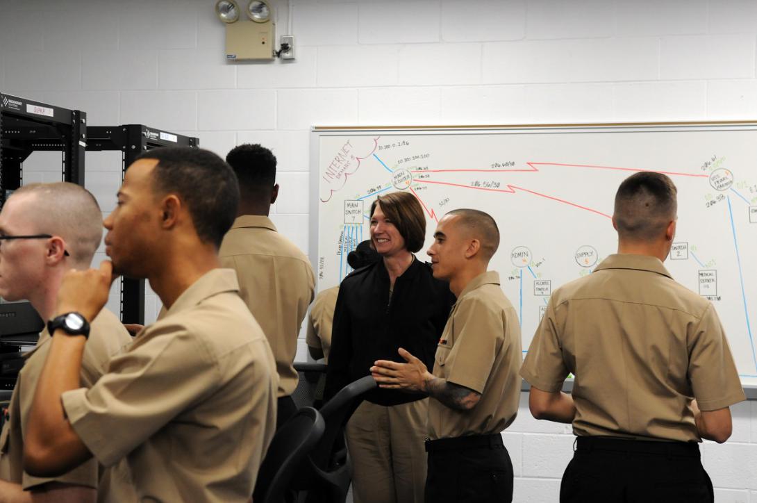 Rear Adm. Nancy Norton, USN, discusses information systems technician training with students at the Center for Information Dominance Unit Corry Station. The students were setting up a mock shipboard network as part of a capstone exercise.