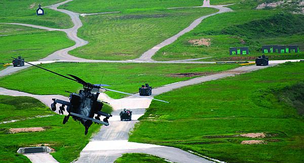 Pilots of an AH-64D Apache fly over soldiers of 1st Battalion, 27th Infantry Regiment, 2nd Stryker Brigade Combat Team, 25th Infantry Division, while preparing to deliver an attack on enemy targets at the Digital Multipurpose Range Complex during Wolfhound Maul. 