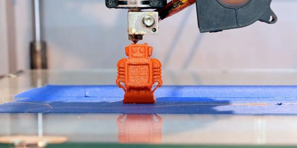 An automatic 3D printer creates a small robot figure on an additive manufacturing platform. The technology is ideally suited for custom manufacture of small parts and items.  Shutterstock/Kyrylo Glivin