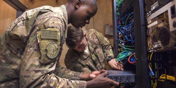 Two U.S. Air Force airmen install network-switch panels at Bagram Airfield, Afghanistan. The Defense Information Systems Agency (DISA) is striving to improve its acquisition processes to procure and deploy innovative information technologies to its customers more quickly.