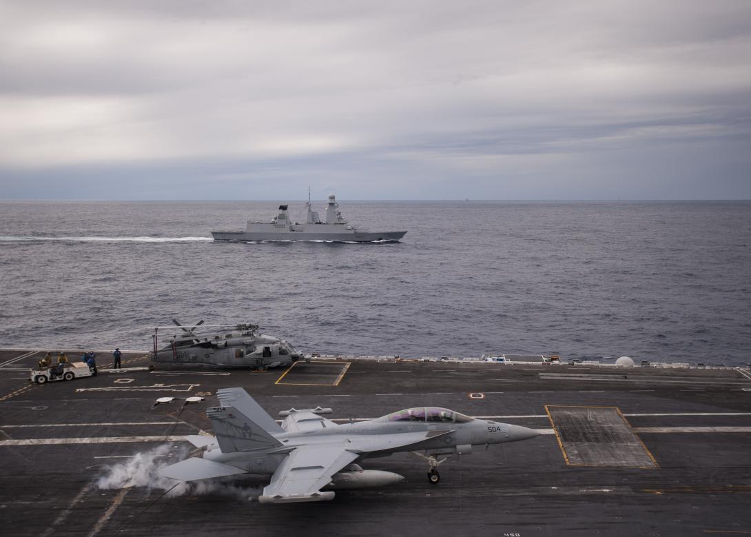 A U.S. Navy EA-18G Growler electronic warfare (EW) aircraft lands on the flight deck of the USS George H.W. Bush during an international exercise that includes the French navy frigate Forbin (rear). Naval exercises with allies and partners help develop ways of integrating EW and related warfighting activities.