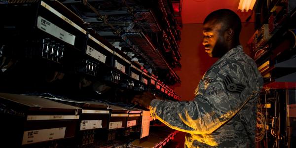A U.S. Air Force cyber transport systems technician works on an electronic equipment rack at Joint Base Charleston, South Carolina. In addition to traditional cyberthreats, the Air Force is seeing increased cyber activity aimed at bringing down its critical infrastructure at bases in the United States.