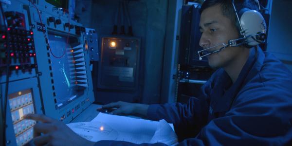 A U.S. Navy cryptologic technician monitors the electromagnetic spectrum of air and surface contacts in the combat information center aboard the guided-missile destroyer USS Ramage in 2014.