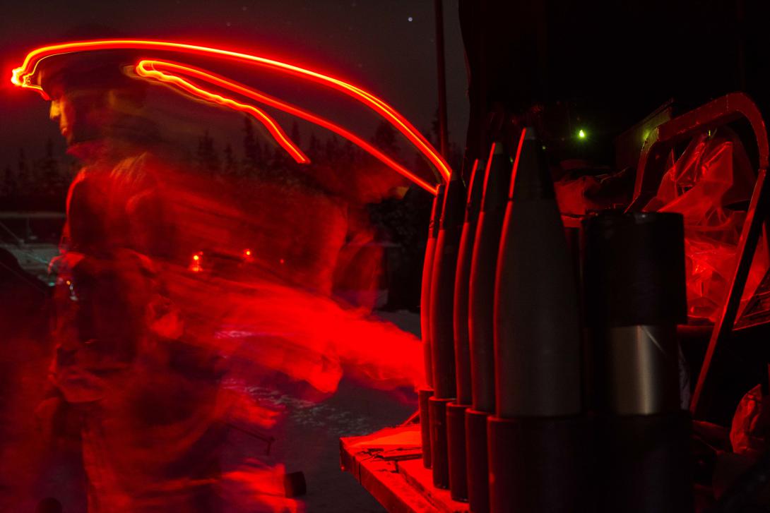 A paratrooper with the 2nd Battalion, 377th Parachute Field Artillery Regiment, 4th Brigade Combat Team (Airborne), 25th Infantry Division, illuminates his area with a red headlamp as he works at a 105 mm howitzer firing point Dec. 10, 2014, at Joint Base Elmendorf-Richardson, Alaska. Paratroopers use the dark, Arctic conditions to gain proficiency in operating in austere environments.