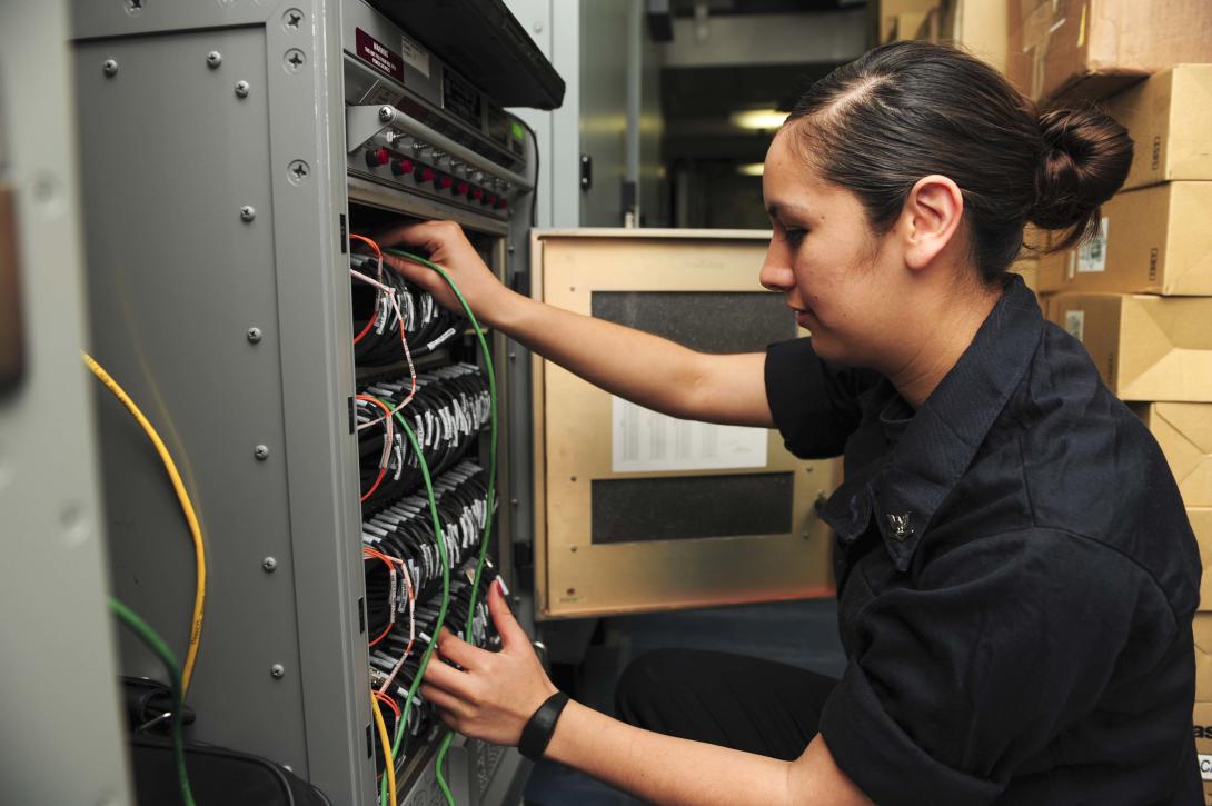 A sailor assigned to the Combat Systems Department aboard the aircraft carrier USS Theodore Roosevelt performs maintenance on a computer server.