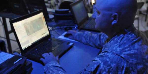 An Army electromagnetic spectrum manager uses a joint spectrum-management planning tool to track mission progress in the field from inside the headquarters tactical operations center as part of Network Integration Evaluation (NIE) in 2014.