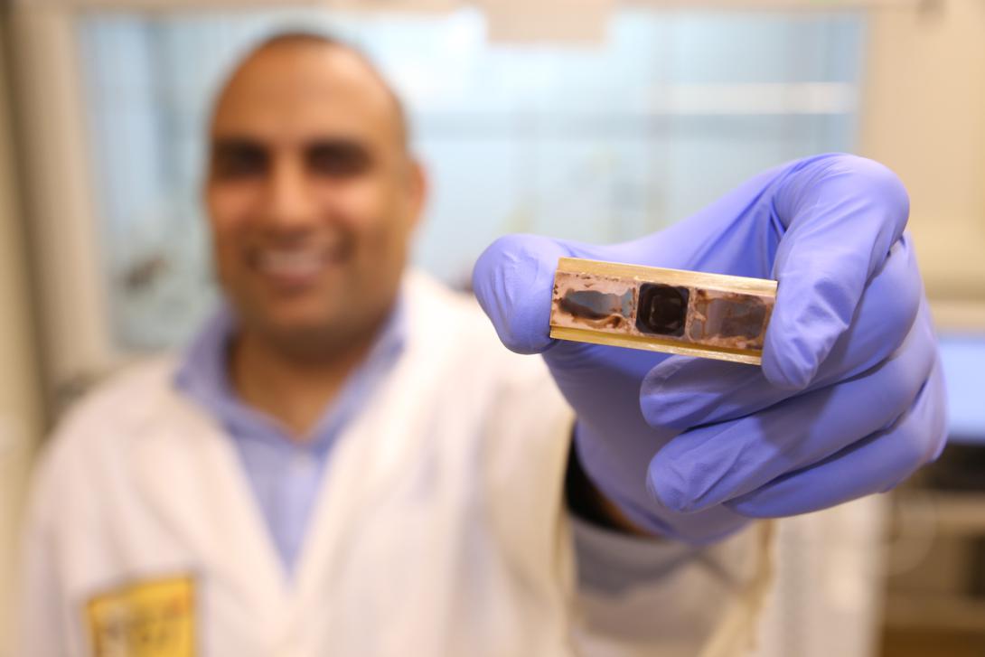 Research scientist Virendra Singh holds a test sample used to measure thermal conductivity and thermal cycle reliability in a new polymer material developed to remove heat from electronic devices.