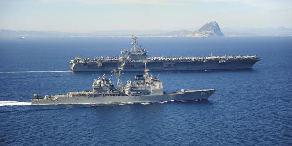 The Ticonderoga-class guided missile cruiser USS Vicksburg, foreground, escorts the Nimitz-class aircraft carrier USS Theodore Roosevelt as they pass the Rock of Gibraltar in the Strait of Gibraltar last March. The Theodore Roosevelt deployed from Norfolk, Virginia, to then make a homeport shift to San Diego at the end of its deployment.