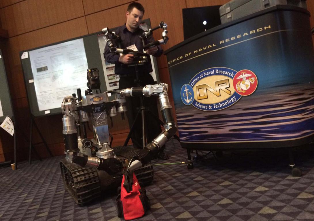 Aaron Nicely, of RE2, manipulates the High Dexterity Robot to retrieve candy from a bag at the Naval Future Force Science and Technology Expo.