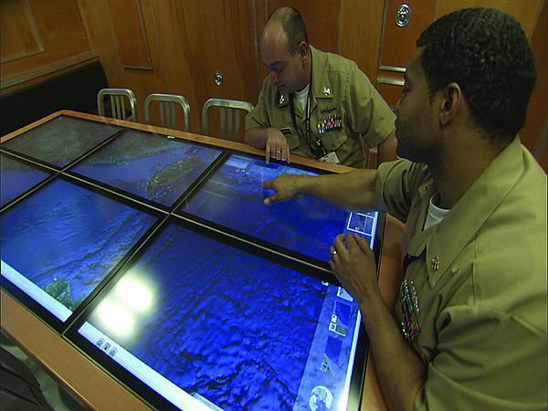 U.S. Navy personnel use an experimental mockup of a submarine situational awareness system based on Google Earth. Navy officials aim to begin deploying the geospatial information system on Virginia-class submarines next year.