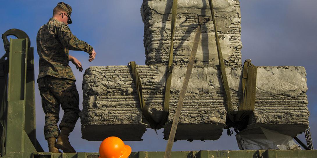 U.S. Marines with 1st Marine Logistics Group (MLG) work together to secure a concrete bridge support column during a 3D concrete printing exercise at Camp Pendleton, California in December.  The 1rst MLG worked with the Marine Corps Systems Command’s Advanced Manufacturing Operations Cell and the Army Corps of Engineers, to print the concrete bridge parts and evaluate the technology for future Marine Corps applications. Credit: U.S. Marine Corps photo by Cpl. Robert Bliss