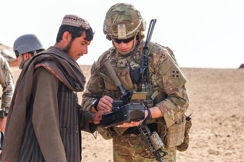While serving in Kandahar, Afghanistan, Sgt. Patrick Cooperider, USA, conducts a fingerprint scan with the Biometrics Automated Toolset during a ground defense area patrol. Photo by Staff Sgt. Neysa Canfield, USA