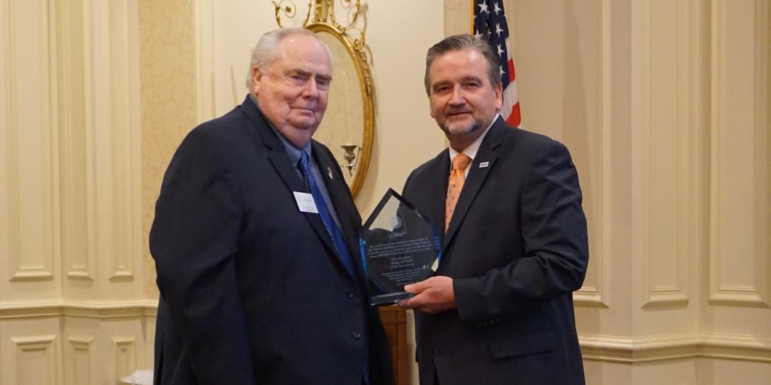 In 2018, the Montgomery Chapter recognizes Chief Master Sgt. Tom Gwaltney, USAF (Ret.) (l), for his contributions to the chapter by naming its Young AFCEAN Award in his honor. Then-Chapter President Brian Knott is also pictured. Chief Gwaltney passed away on March 15, 2020. Credit: Montgomery Chapter