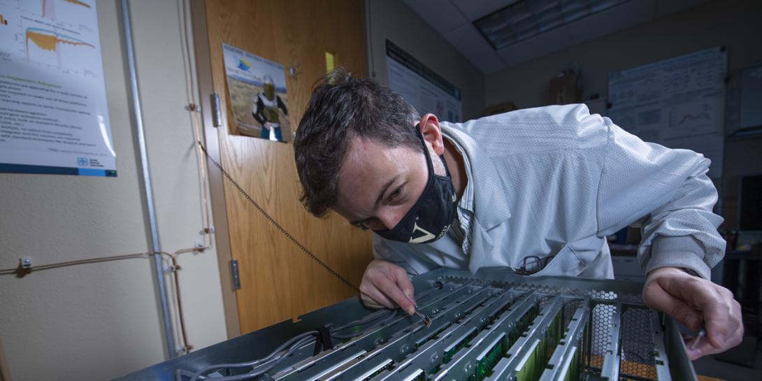 Sandia National Laboratories researcher J. Darby Smith examines computer boards containing artificial neurons Intel Corp designed. (Photo by Regina Valenzuela)