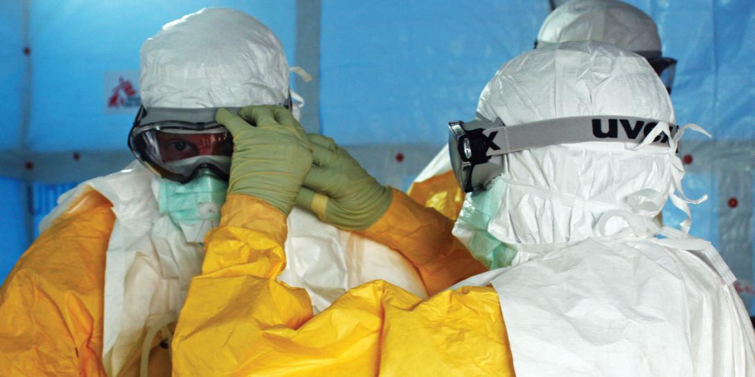 Health care providers adjust personal protective equipment as they prepare to enter a facility treating the Ebola virus in Liberia. Future pandemics could come from natural viruses or biological weapons developed by sophisticated nations; but whichever the source, opportunistic foes will take advantage of their effects to wreak further havoc on victim nations. (U.S. Army photo)