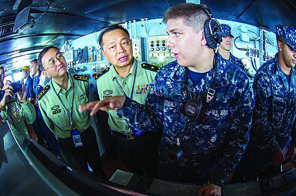 Seaman Alex Snyder, USN, right, explains the functions of the helm on the navigation bridge of the aircraft carrier USS George Washington to Maj. Gen. Chen Weizhan, deputy commander of the People’s Liberation Army, Hong Kong Garrison, center, and Col. Li Jiandang, Hong Kong Garrison liaison officer during a distinguished visitor embark.